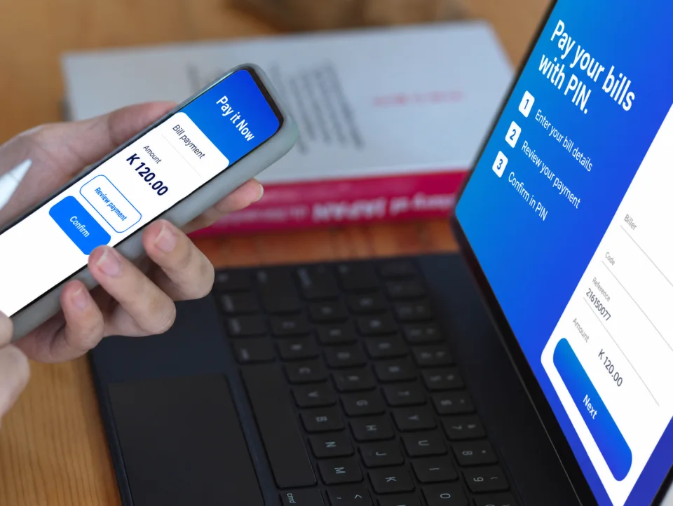 Confirming a K 120.00 bill payment in the PIN app, with the bill payment steps on a laptop behind