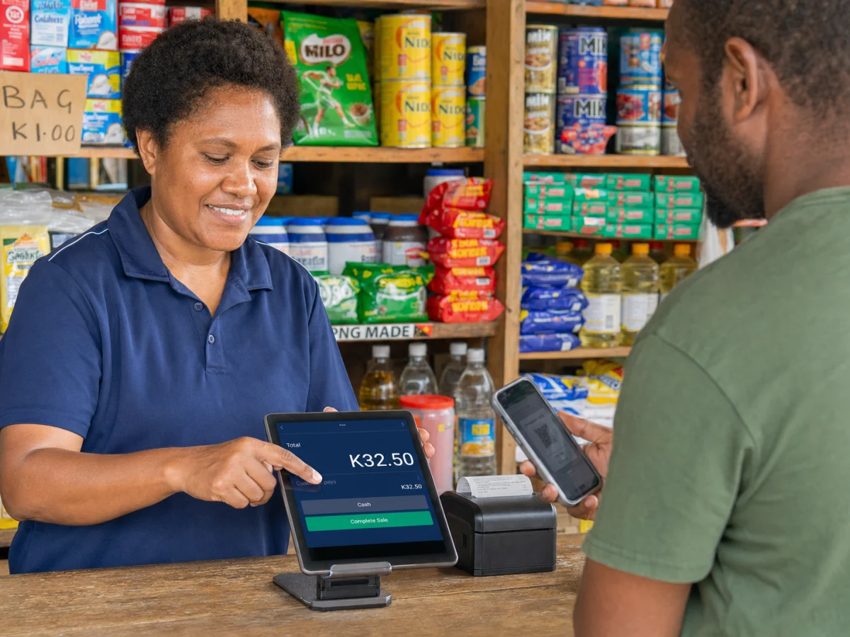 Shopkeeper completing a Kina sale on a tablet POS at a Papua New Guinea trade store